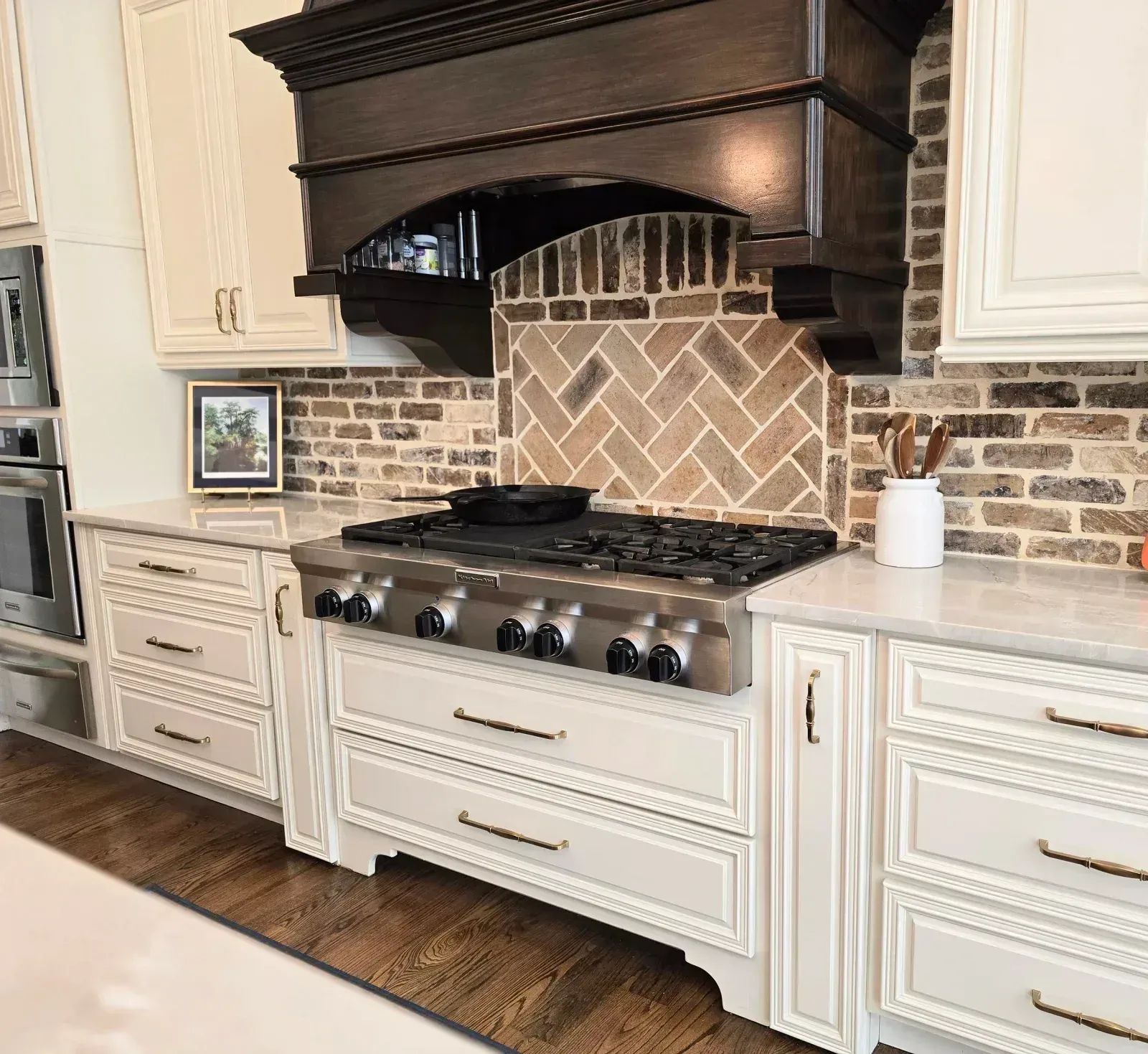 Painted kitchen cabinets around a range with a wood hood